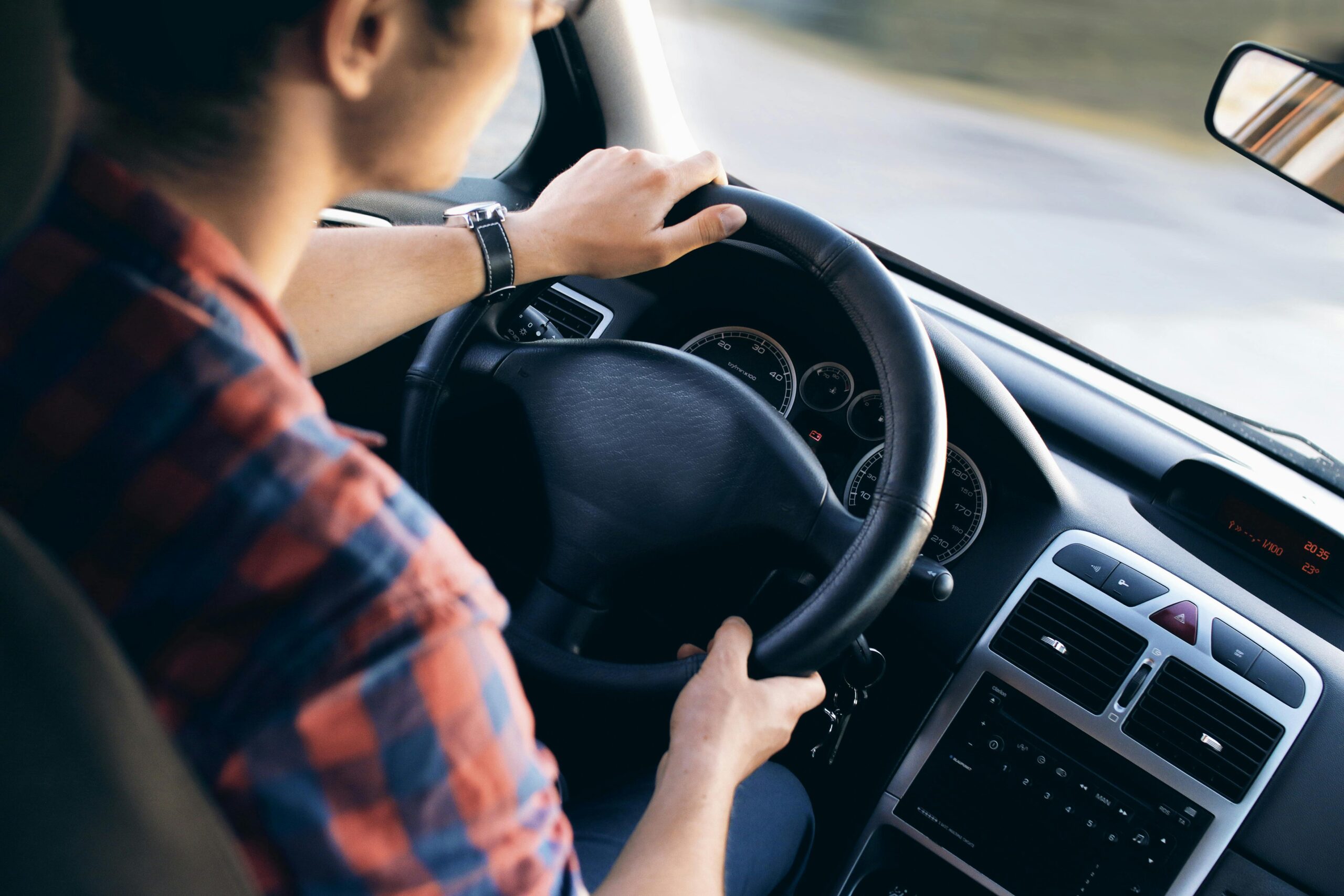 About Close-up view of a man driving a modern car, showing dashboard and steering details.